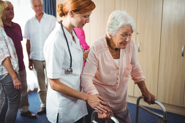 Sjuksköterskan att hjälpa en pensionerad kvinna att gå — Stockfoto