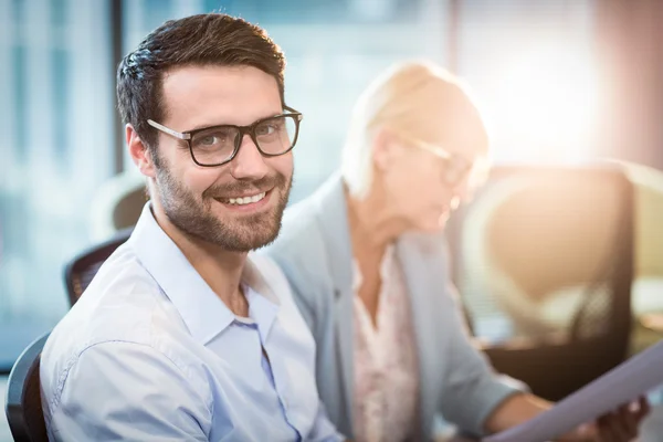 Homem sorrindo enquanto seu colega lendo documento — Fotografia de Stock