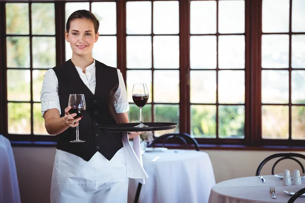 Portrait de serveuse souriante offrant un verre de vin rouge — Photo