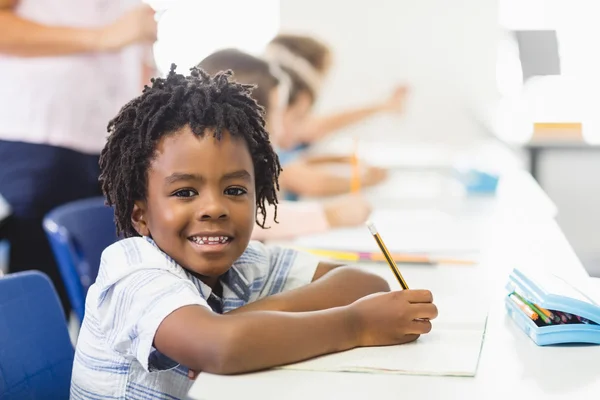 Skolan pojke gör läxor i klassrummet — Stockfoto