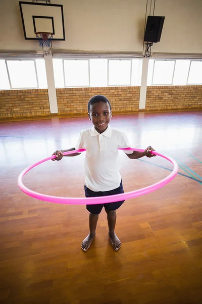 Portrait of boy playing with hula hoop in school gym — Stock Photo, Image