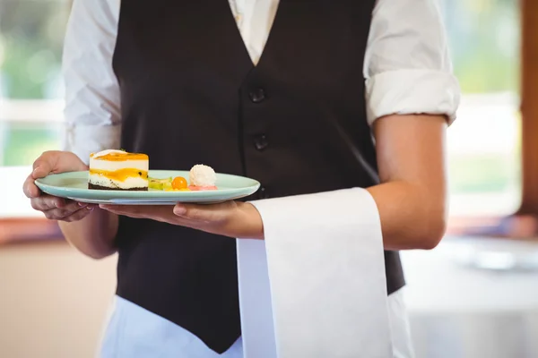 Servitrisen innehar en tallrik med tårtor — Stockfoto