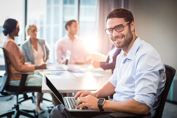 Hombre usando el ordenador portátil mientras compañero de trabajo interactúa —  Fotos de Stock