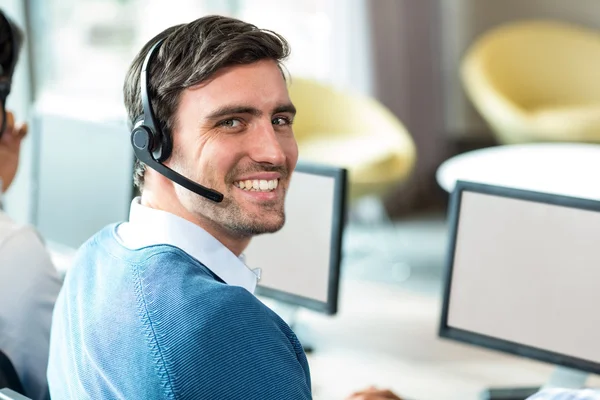 Jonge man aan het werk op computer met headset — Stockfoto