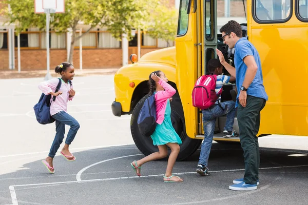 Insegnante dando il cinque ai bambini mentre entrano in autobus — Foto Stock