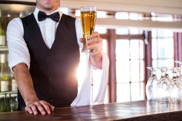 Cantinero ofreciendo un vaso de cerveza en el mostrador del bar — Foto de Stock