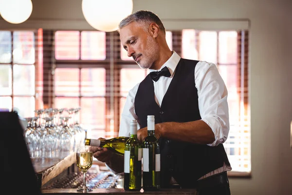 Barman derramando vinho tinto em um copo — Fotografia de Stock