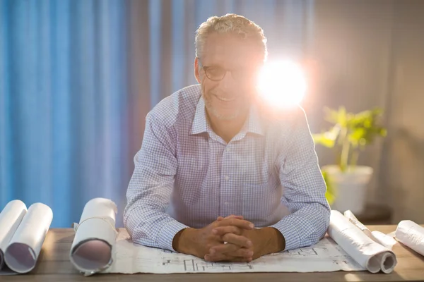 Man zit met blauwdruk achter zijn Bureau — Stockfoto