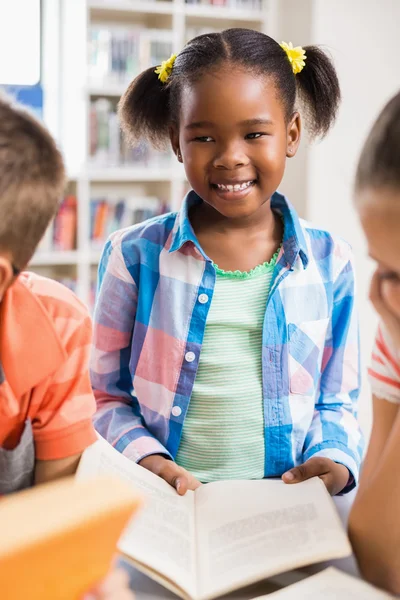 Schoolgirl reading a book in library — Stock Photo, Image