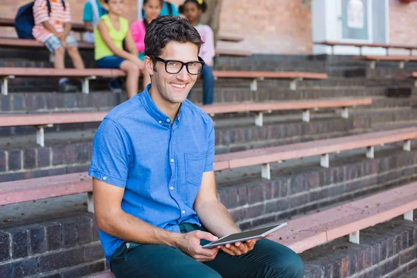 Retrato do professor sentado no banco e usando tablet digital — Fotografia de Stock