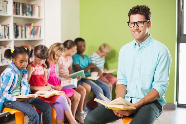 Leerkracht en kinderen lezen boeken in bibliotheek — Stockfoto