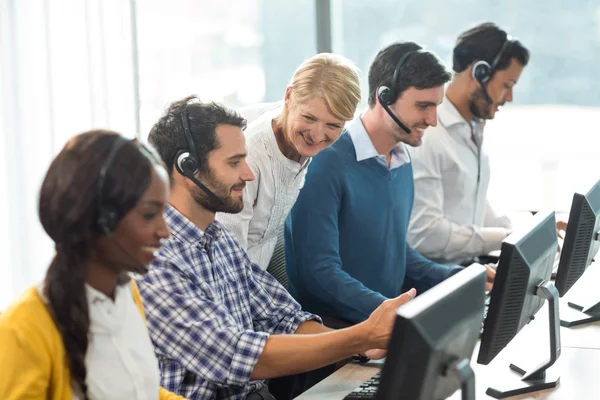 Equipe de colegas trabalhando em sua mesa com fone de ouvido — Fotografia de Stock