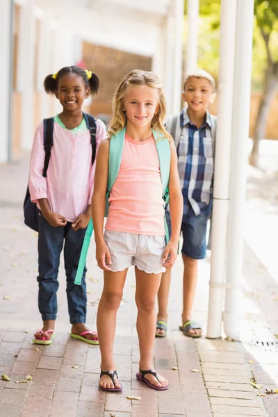 Crianças da escola sorrindo em pé no corredor da escola com o braço ao redor — Fotografia de Stock