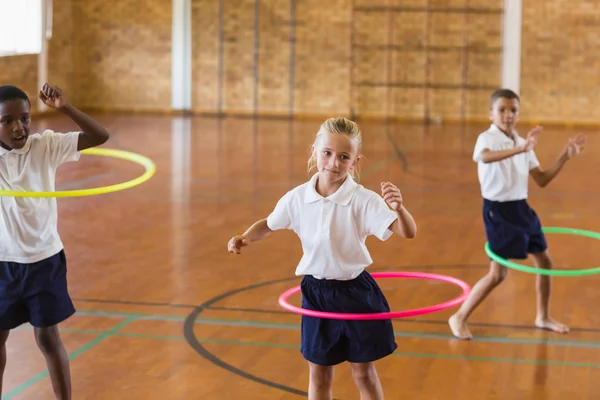 Students playing with hula hoop in school gym — Stock Photo, Image