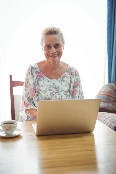 Leende senior kvinna använder en bärbar dator — Stockfoto