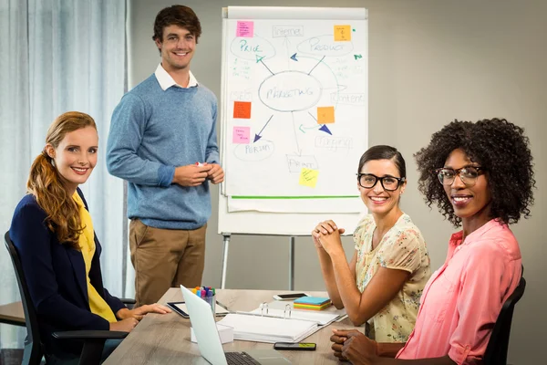 Hombre discutiendo diagrama de flujo en pizarra blanca con compañeros de trabajo — Foto de Stock