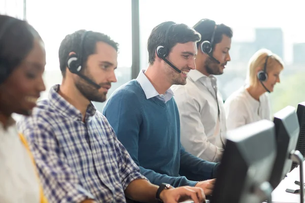 Team van collega's die werken op hun bureau met headset — Stockfoto