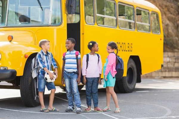 Niños sonrientes de pie juntos frente al autobús escolar — Foto de Stock