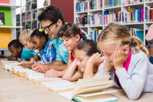 Nauczyciel i dzieci, czytanie książki w bibliotece — Zdjęcie stockowe