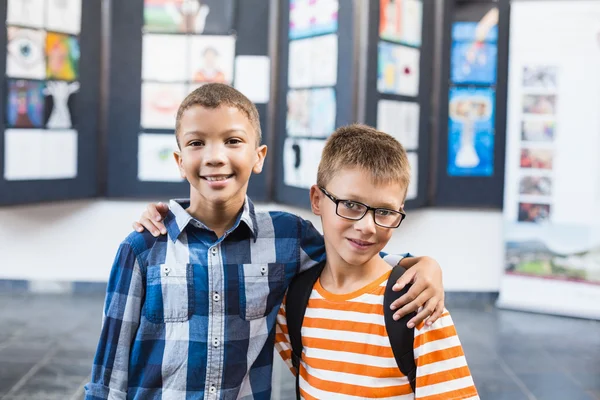 Crianças da escola sorrindo de pé com o braço ao redor em sala de aula — Fotografia de Stock