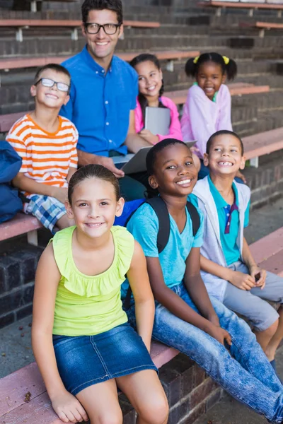 Portrait of teacher and kids sitting on bench — Stock Photo, Image