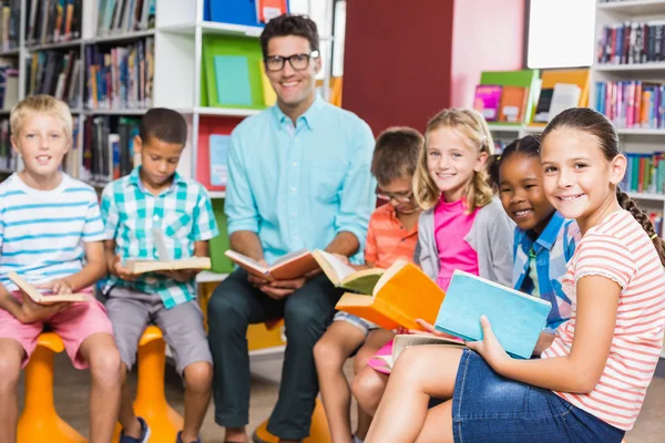 Profesor y niños leyendo libro en la biblioteca —  Fotos de Stock