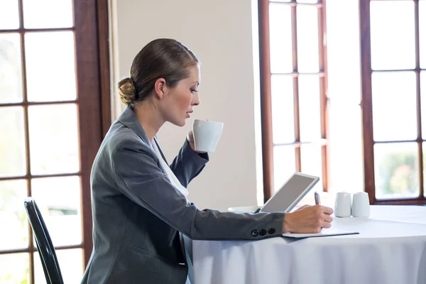 Kvinnan arbetar och dricka en kopp kaffe — Stockfoto