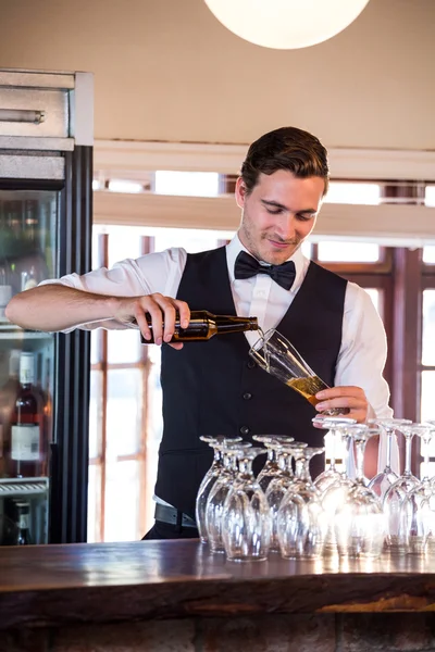 Barman sorrindo derramando uma cerveja em um copo — Fotografia de Stock