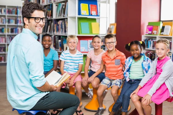 Δάσκαλος και τα παιδιά που κάθεται στη βιβλιοθήκη — Φωτογραφία Αρχείου