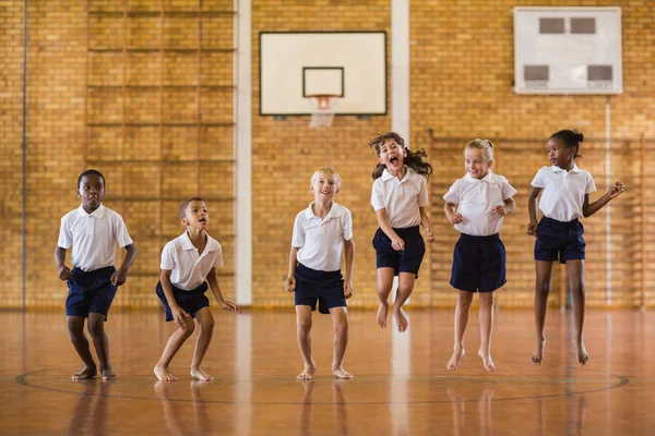 Группа учеников, прыгающих в школьном спортзале — стоковое фото
