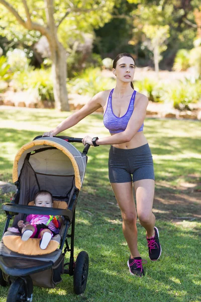 Jovem mulher andando com carrinho de bebê — Fotografia de Stock