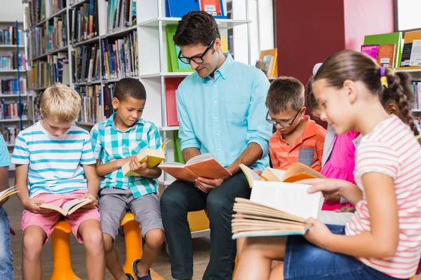 Nauczyciel i dzieci, czytanie książki w bibliotece — Zdjęcie stockowe