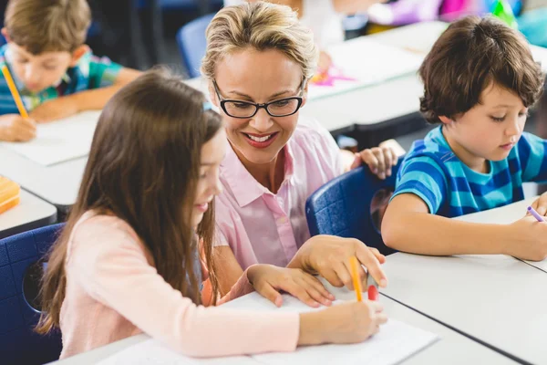 Lehrerin hilft Mädchen bei den Hausaufgaben im Klassenzimmer — Stockfoto