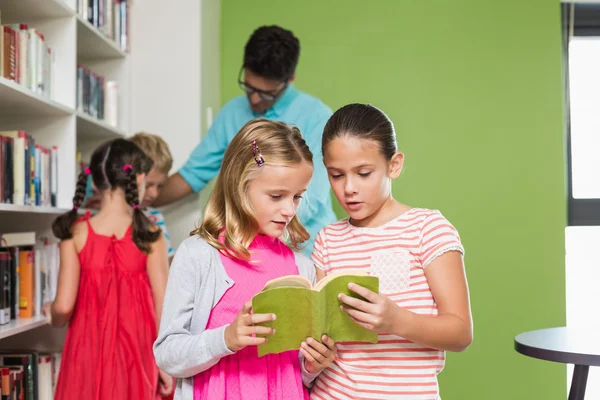 Crianças lendo livro na biblioteca — Fotografia de Stock