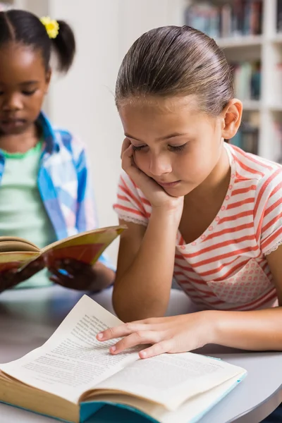 Školačka čtení knihy v knihovně — Stock fotografie