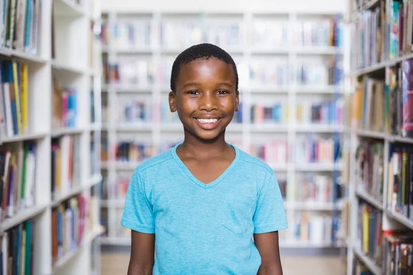 Lycklig skolpojke står i biblioteket — Stockfoto