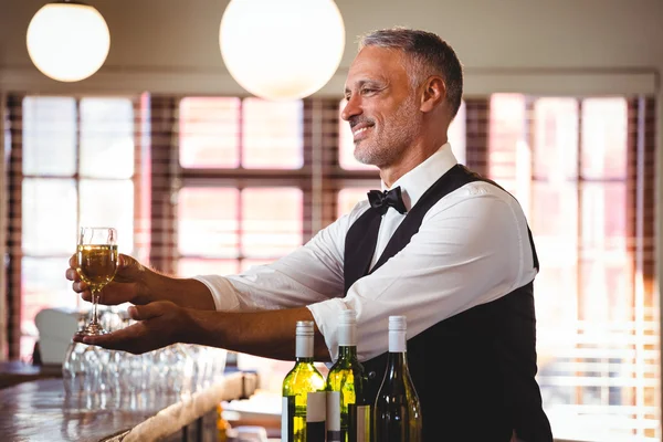 Χαμογελώντας μπάρμαν προσφέροντας ένα ποτήρι κρασί στο μπαρ μετρητή — Φωτογραφία Αρχείου
