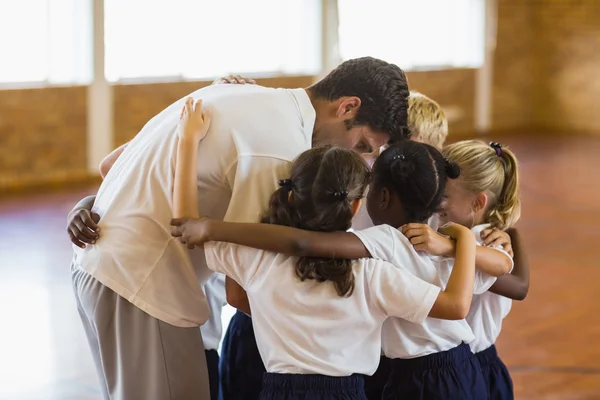 Sport teacher and students forming a huddle