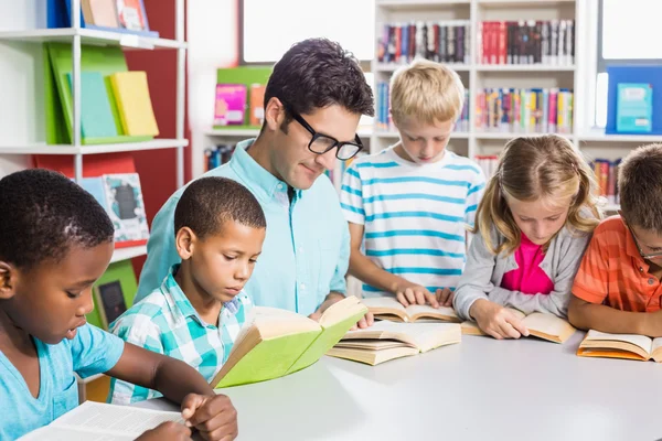 Profesor y niños leyendo libro en la biblioteca — Foto de Stock