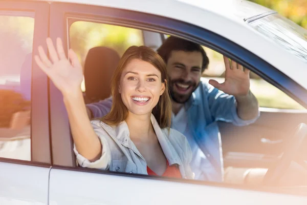 Gelukkige paar zwaaien handen terwijl in auto — Stockfoto