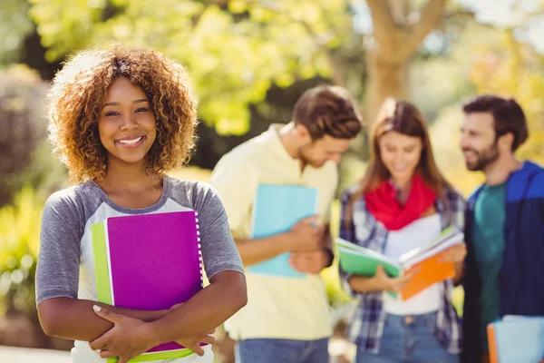 Retrato de chica universitaria sosteniendo notas con amigos en el fondo —  Fotos de Stock