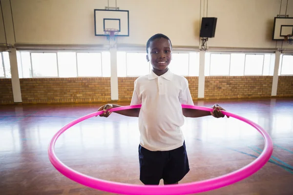 Portrait of boy playing with hula hoop in school gym — Stock Photo, Image