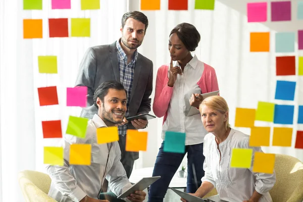 Gente de negocios mirando notas adhesivas — Foto de Stock