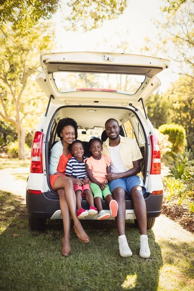 Zittend op hun auto en gelukkige familie — Stockfoto