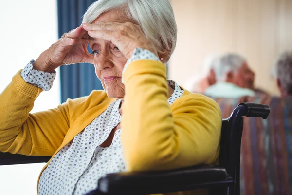 Старша жінка в інвалідному візку виглядає стурбованою — стокове фото