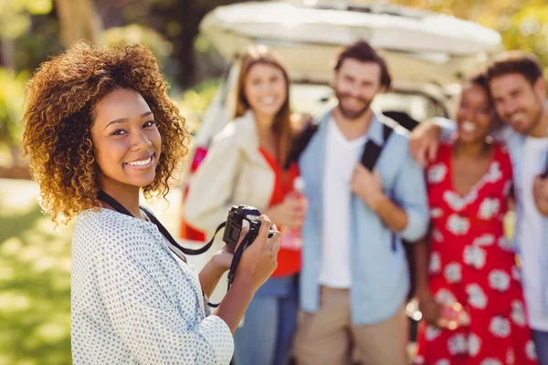 Mujer sonriente haciendo clic en una foto de sus amigos — Foto de Stock