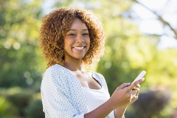 Mulher feliz usando telefone celular no parque — Fotografia de Stock