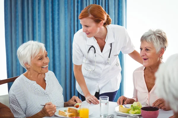 Pielęgniarka, patrząc na starszy osoba podczas śniadania — Zdjęcie stockowe