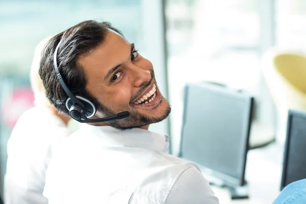 Young man working on computer with headset — Stock Photo, Image