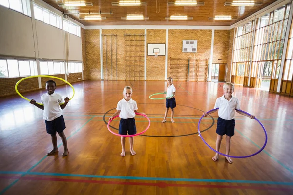 Studenti s hula hoop ve školní tělocvičně — Stock fotografie